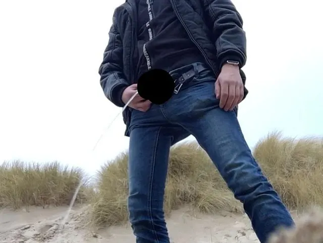 young man urinates in the dunes